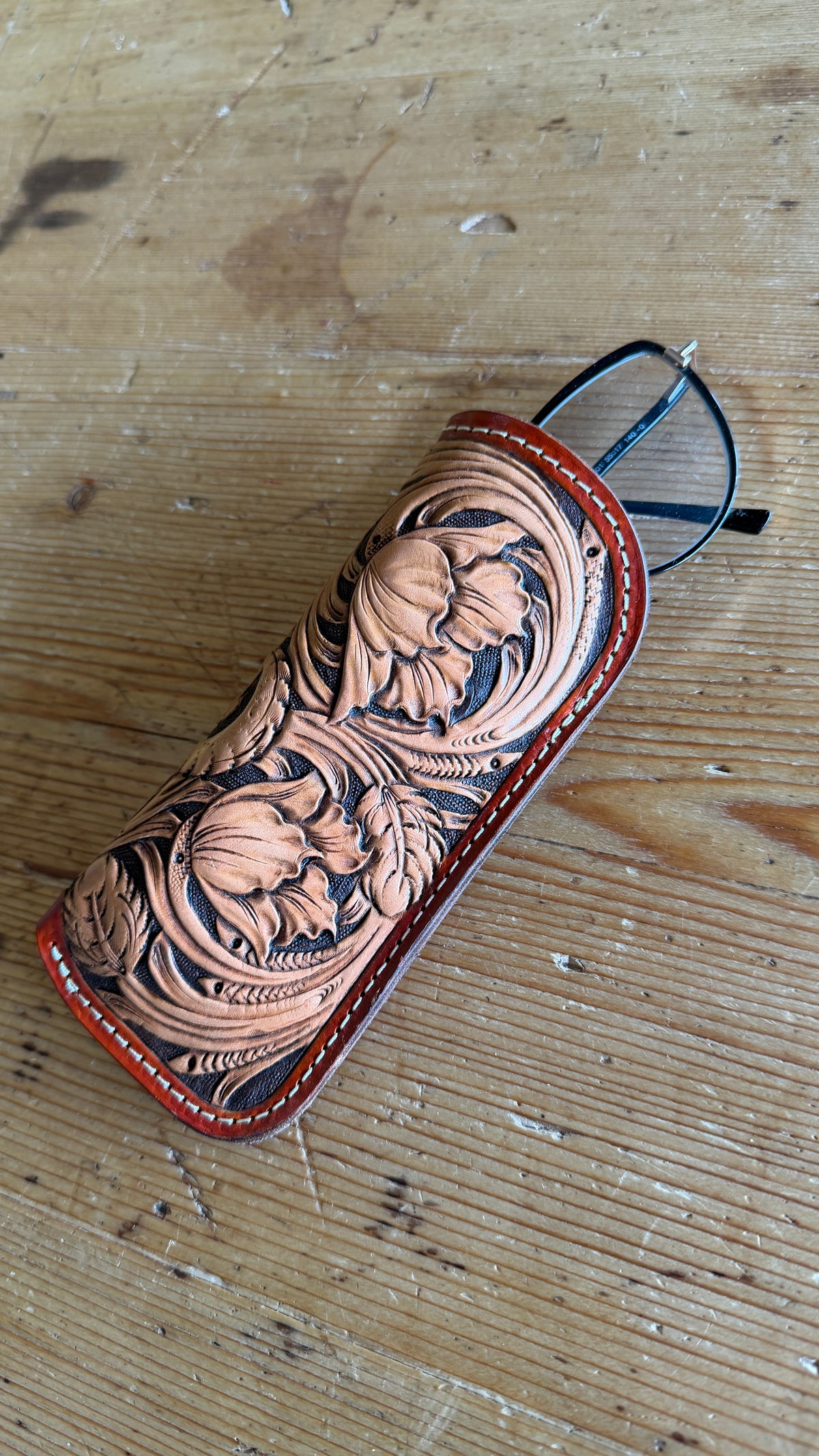 Hand-tooled leather glasses case front view with glasses