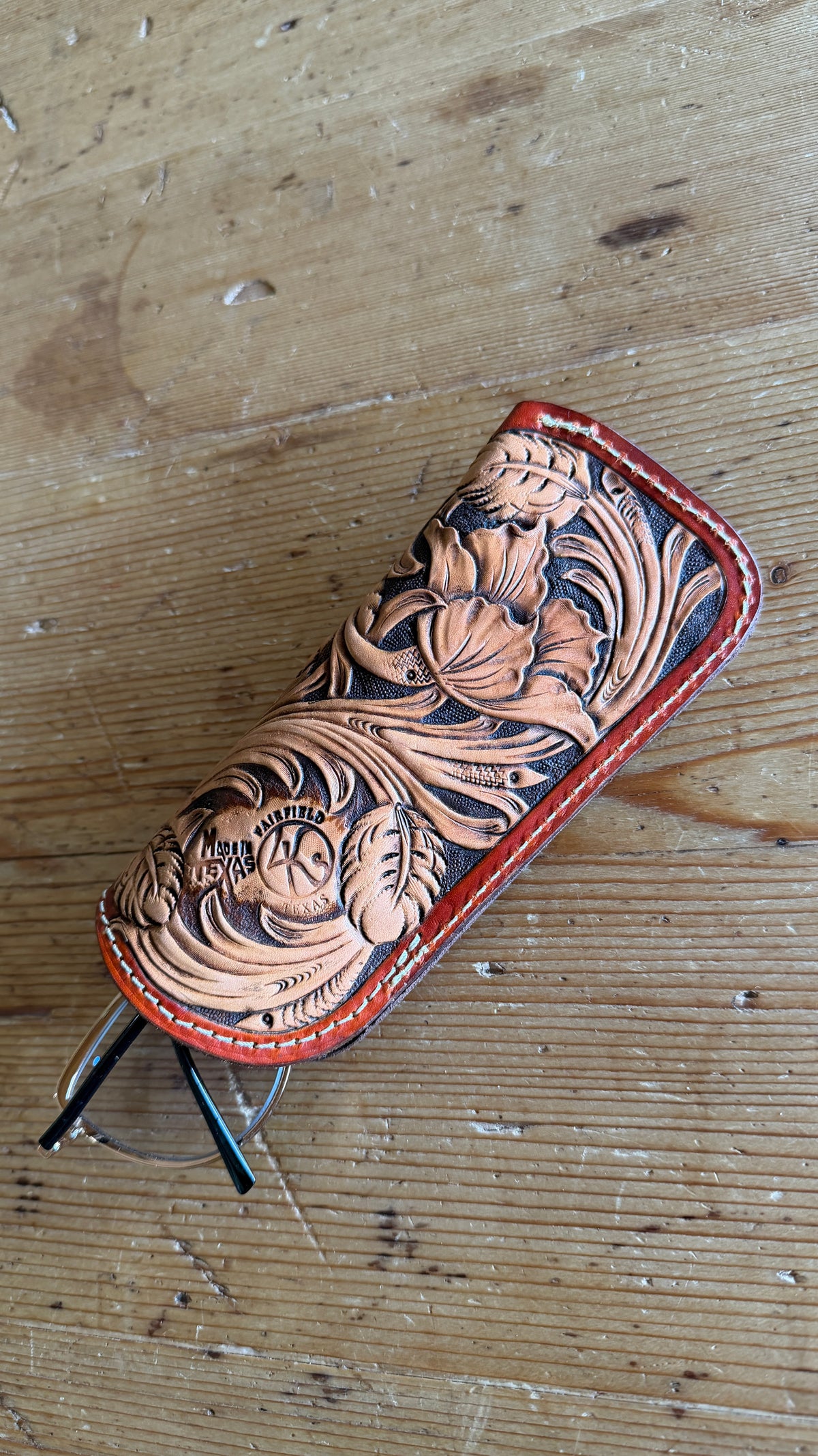 Hand-tooled leather glasses case back view showing brand stamp